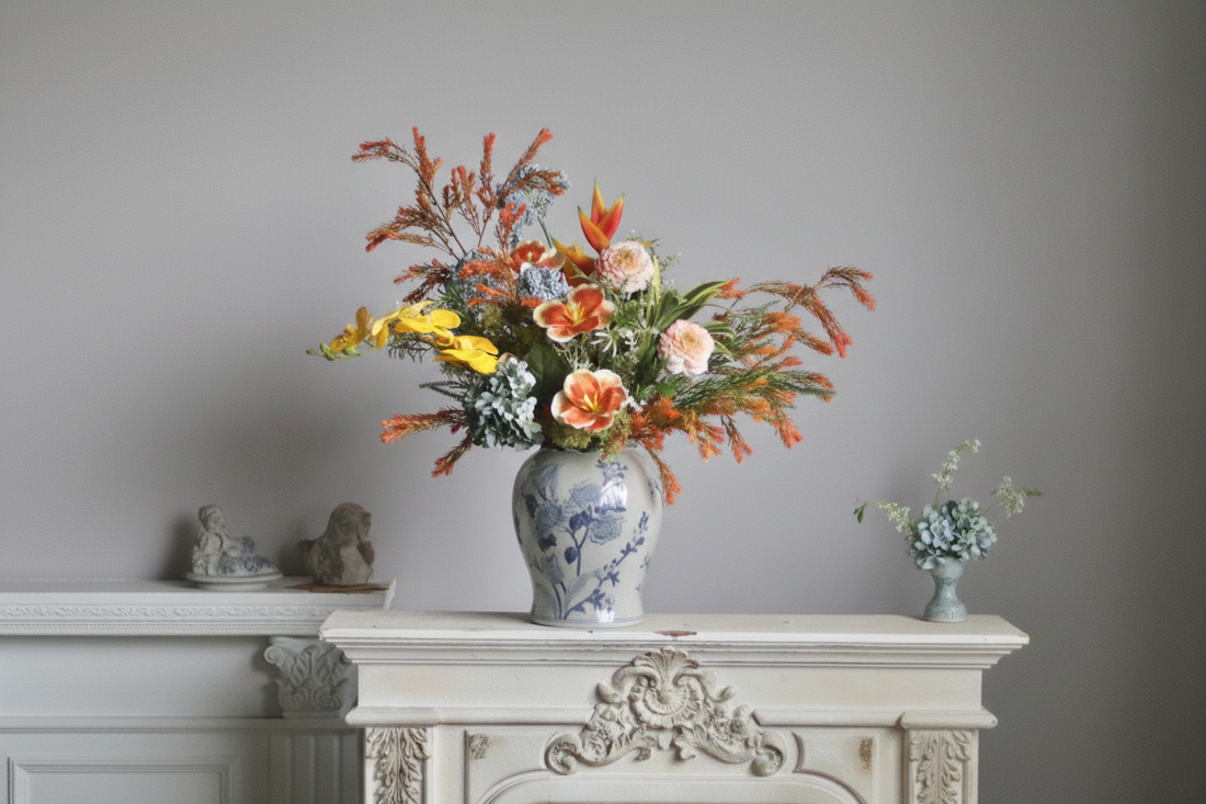 Vibrant faux floral arrangement with orange tulips, yellow orchids, bird of paradise and peach roses in a blue and white chinoiserie vase on a French baroque fireplace mantel