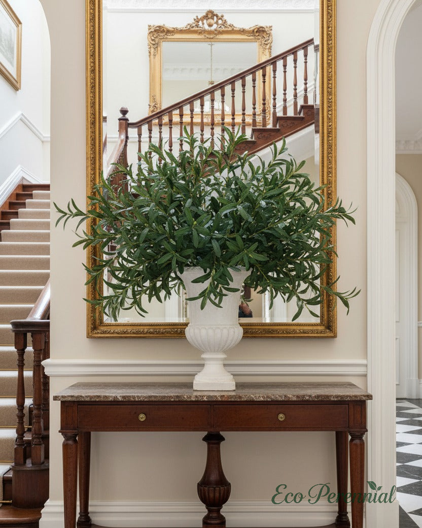 Eco Perennial artificial olive branches with soft grey-green leaves in a tall frosted glass vase on a white marble kitchen island in an English country interior