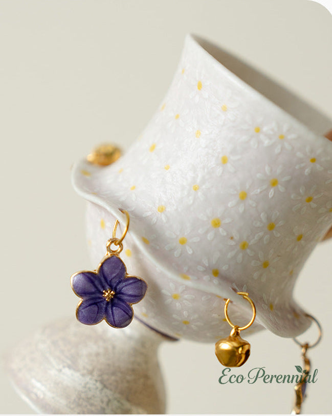 Lavender flower charm and gold bell pendant detail on artisan ceramic teacup — Eco Perennial
