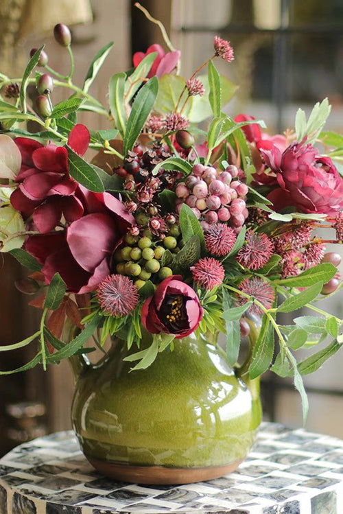 Deep burgundy silk ranunculus bouquet in a vintage vase, moody floral arrangement for dramatic home decor by Eco Perennial.
